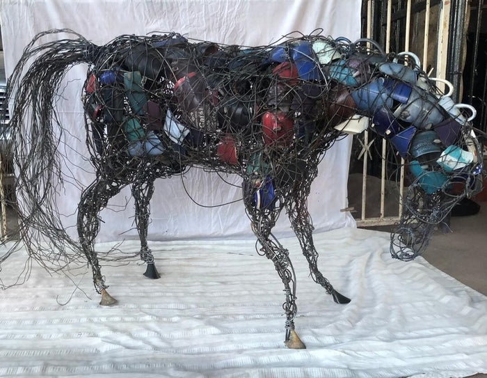 Life-size horse in dark wire with blue and red bottle caps
